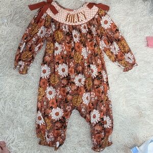 Smock jumpsuit with the name “Riley” on it